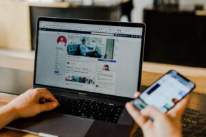 laptop and phone using Facebook
